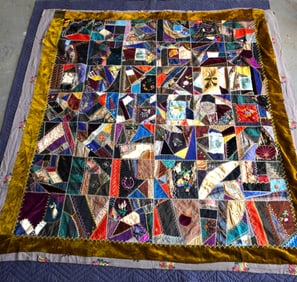 A Victorian crazy quilt decorated with embroidery work and hand paintings including flowers,
