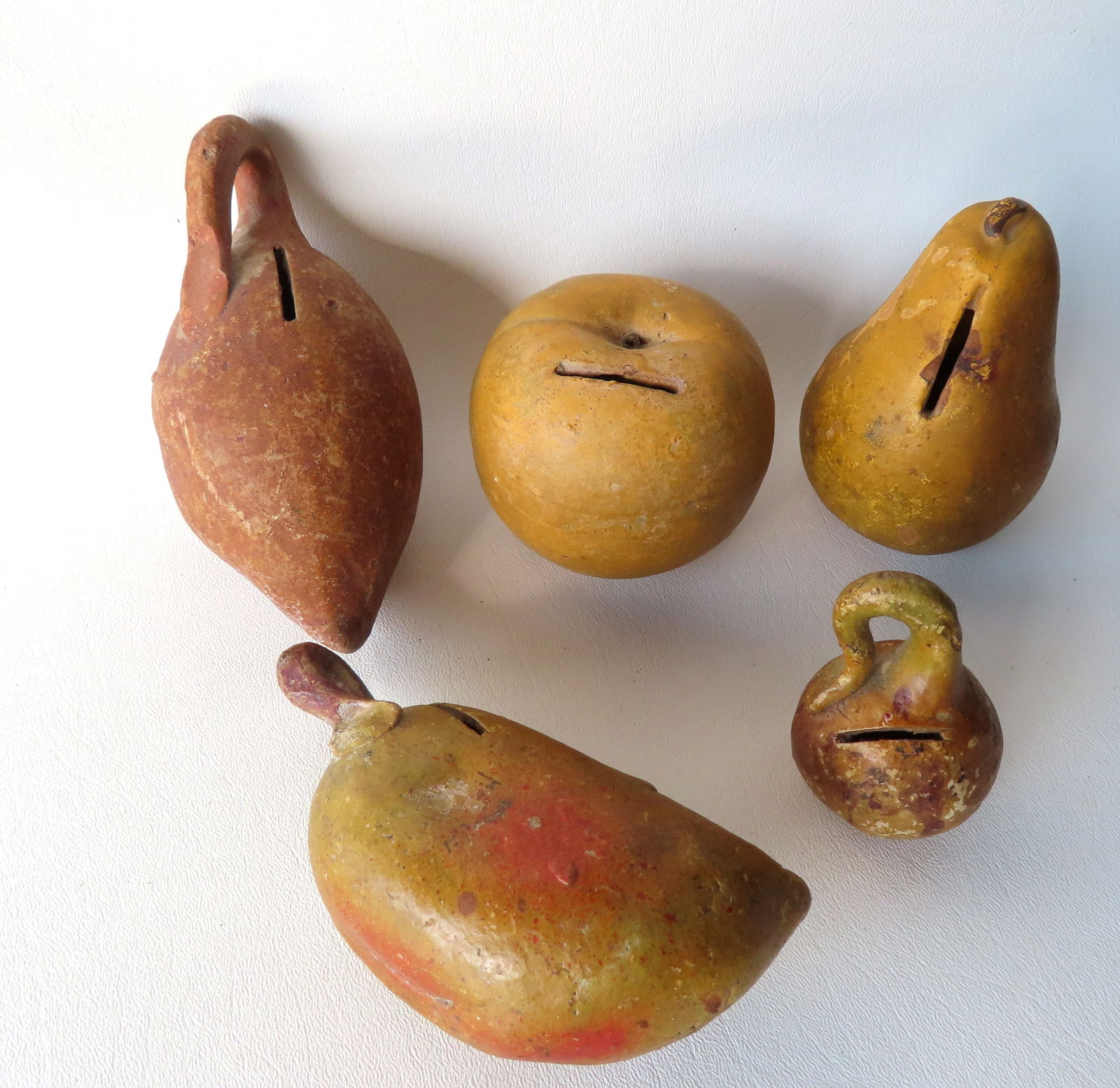 Grouping of 5 redware fruit and vegetable banks in original paint, 19th century. Includes an apple,: Grouping of 5 redware fruit and vegetable banks in original paint, 19th century. Includes an apple, pear, small gourd, yam, and an unknown mustard colored vegetable. All with some paint blemishes, but