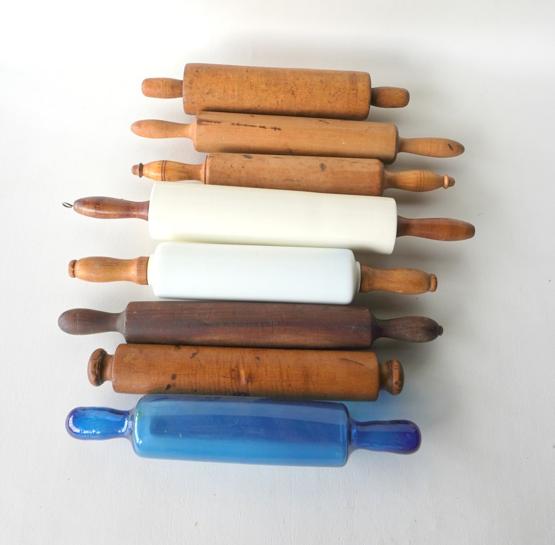 A grouping of 8 vintage rolling pins including in 1 in white porcelain, 1 in white molded milkglass,: A grouping of 8 vintage rolling pins including in 1 in white porcelain, 1 in white molded milkglass, 1 in blue semi-transparent blown glass, and 5 in maple and other woods. All late 19th to early 20th