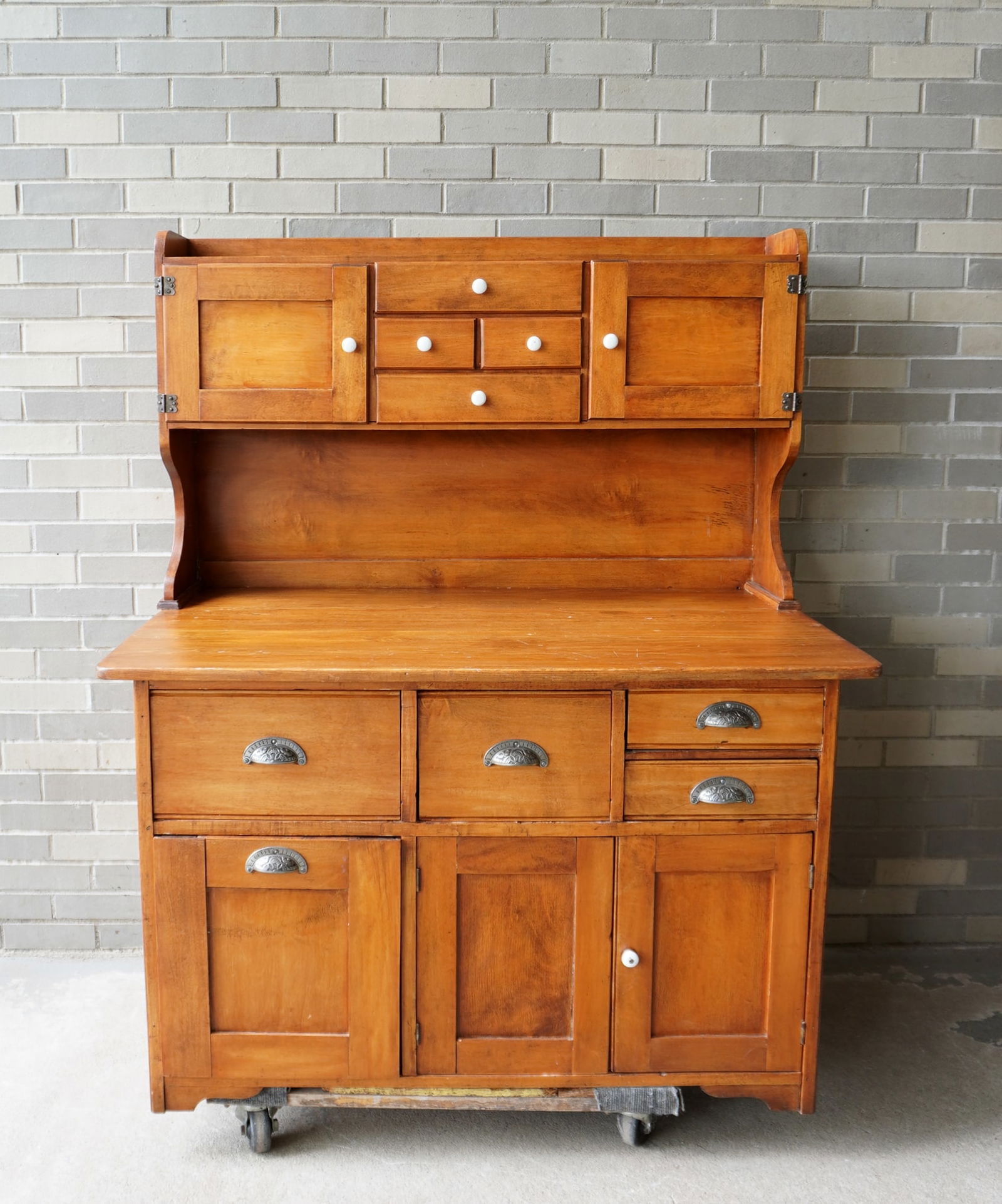 Two part maple baker's cabinet. The upper section with 4 drawers flanked by 2 doors, over large work: Two part maple baker's cabinet. The upper section with 4 drawers flanked by 2 doors, over large work surface over base with 4 drawers over dough drawer adjacent to 2 door storage area. Good clean cond