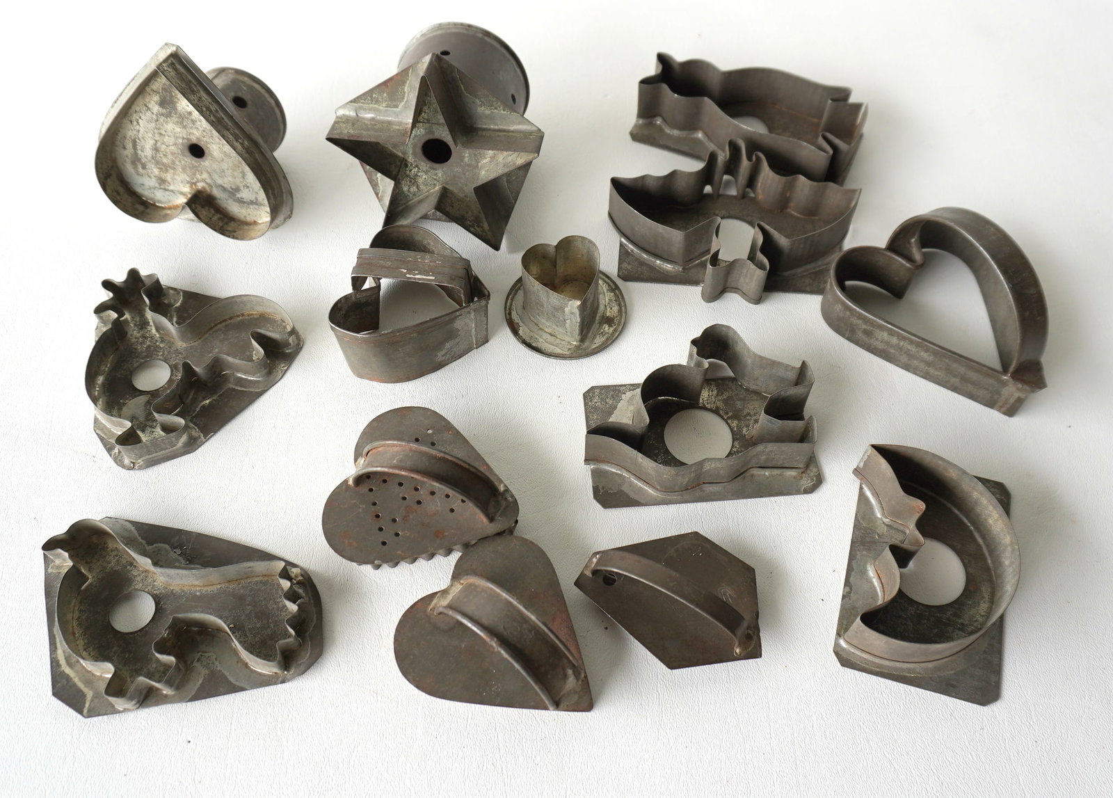 A grouping of 14 early tin figural cookie cutters including: Bat, hearts, star, cat, birds,: A grouping of 14 early tin figural cookie cutters including: Bat, hearts, star, cat, birds, man-in-the-moon, rooster, etc. Most in very good condition, 19th century. The largest, the star with attache