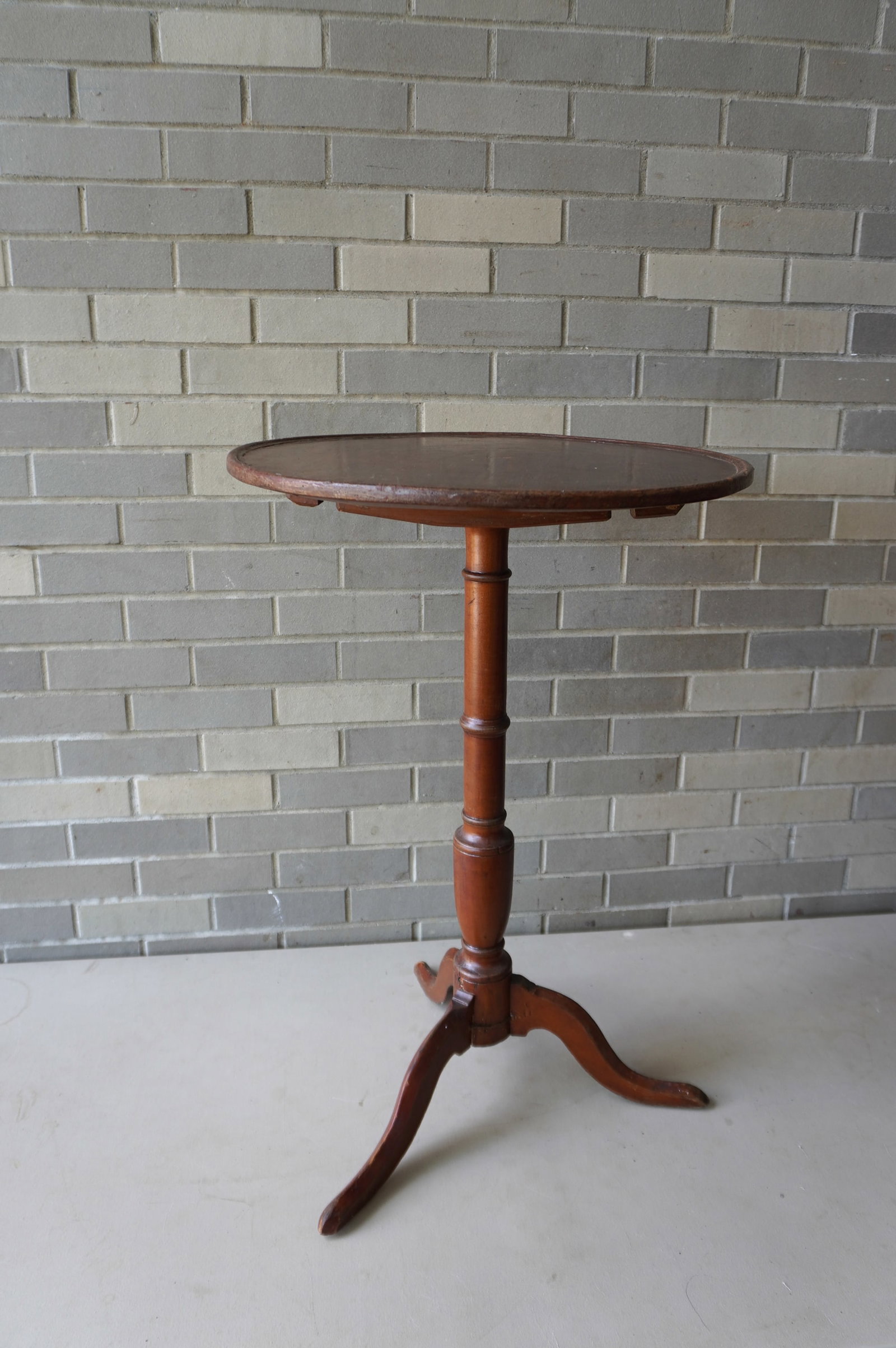 A Queen Ann pine dish top candlestand with tilt top, turned column supported by 3 shaped snake feet,: A Queen Ann pine dish top candlestand with tilt top, turned column supported by 3 shaped snake feet, late 18th century. The base with old repairs, refinished, else good condition. 20 1/2" diameter of 