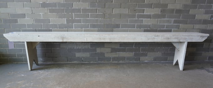 A long primitive pine bench in old white paint, probably mid to late 20th century. Very good