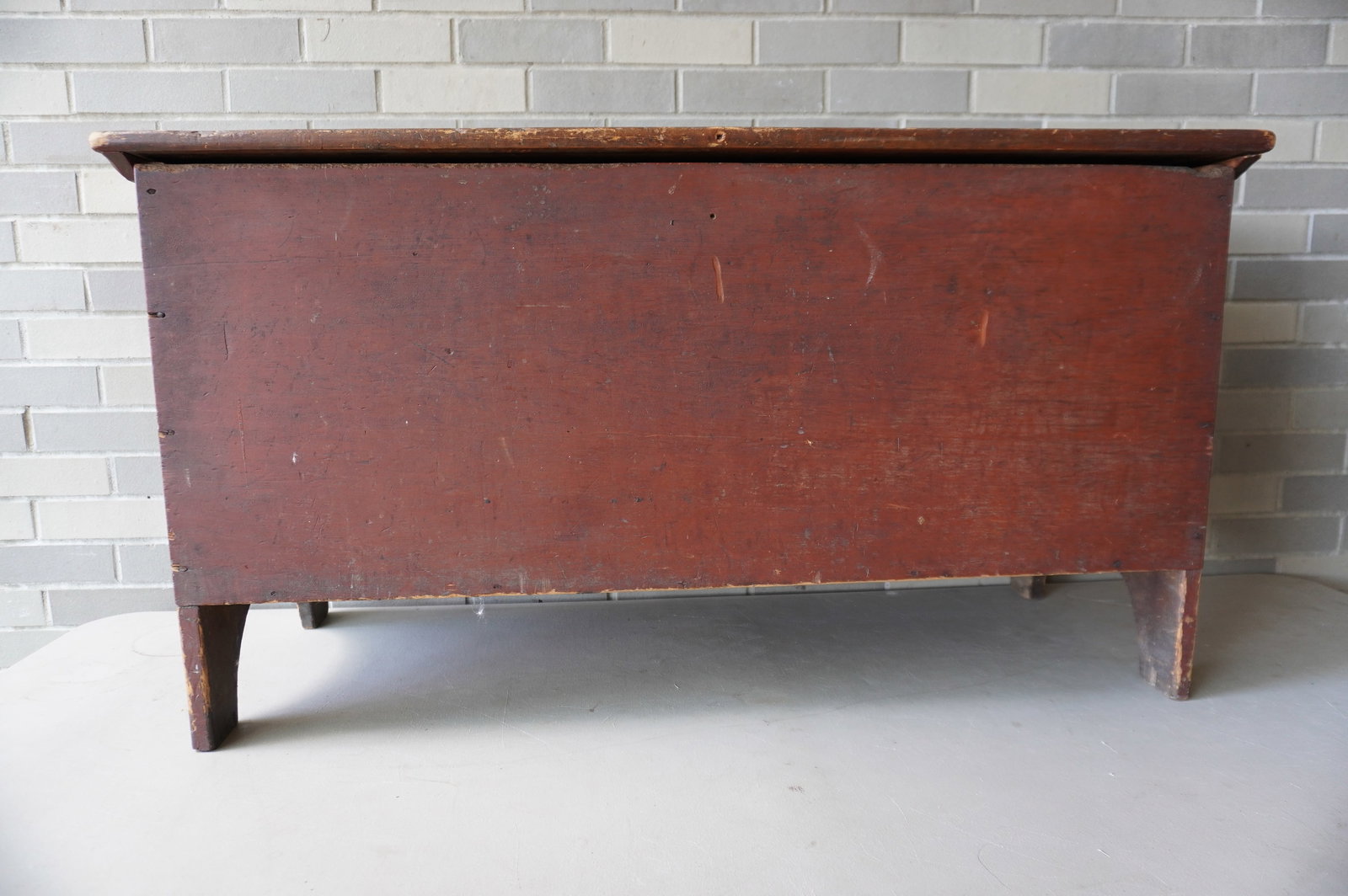 A Queen Ann blanket box in original red paint, cotterpin hinges on lid with crack, original lid: A Queen Ann blanket box in original red paint, cotterpin hinges on lid with crack, original lid cleats, and half-moon cutouts on side. Overall good condition. Measures 44"W x 17"D x 23 1/2"H.