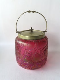 An art glass biscuit jar, purple and gold iridescent colors, having a silver plated handle and lid,