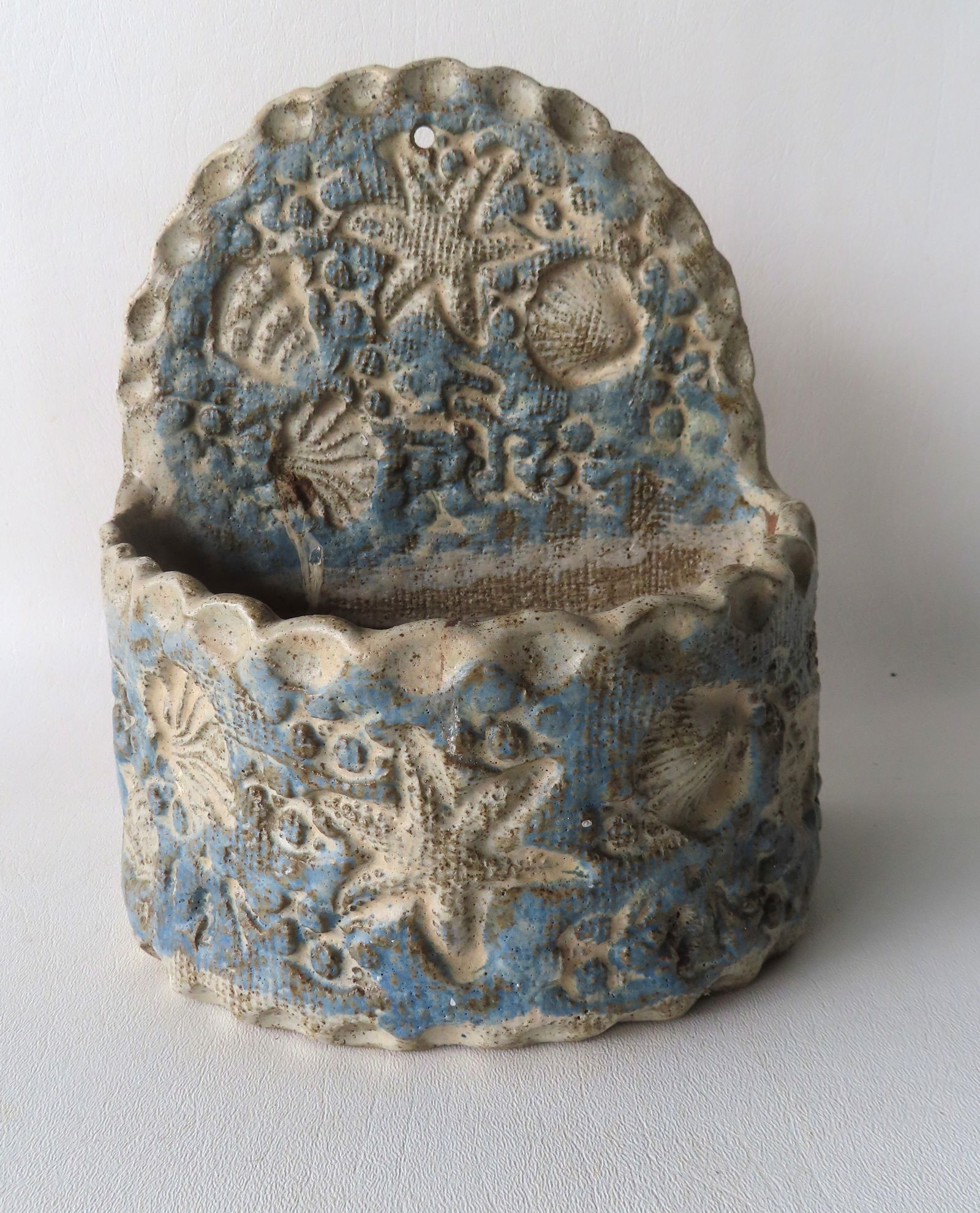 A stoneware outdoor wall hanging planter, with marine designs pressed into stoneware, hand made and: A stoneware outdoor wall hanging planter, with marine designs pressed into stoneware, hand made and hand painted (light blue and off-white colors) and decorated with star fish, sea shells, etc. Very g