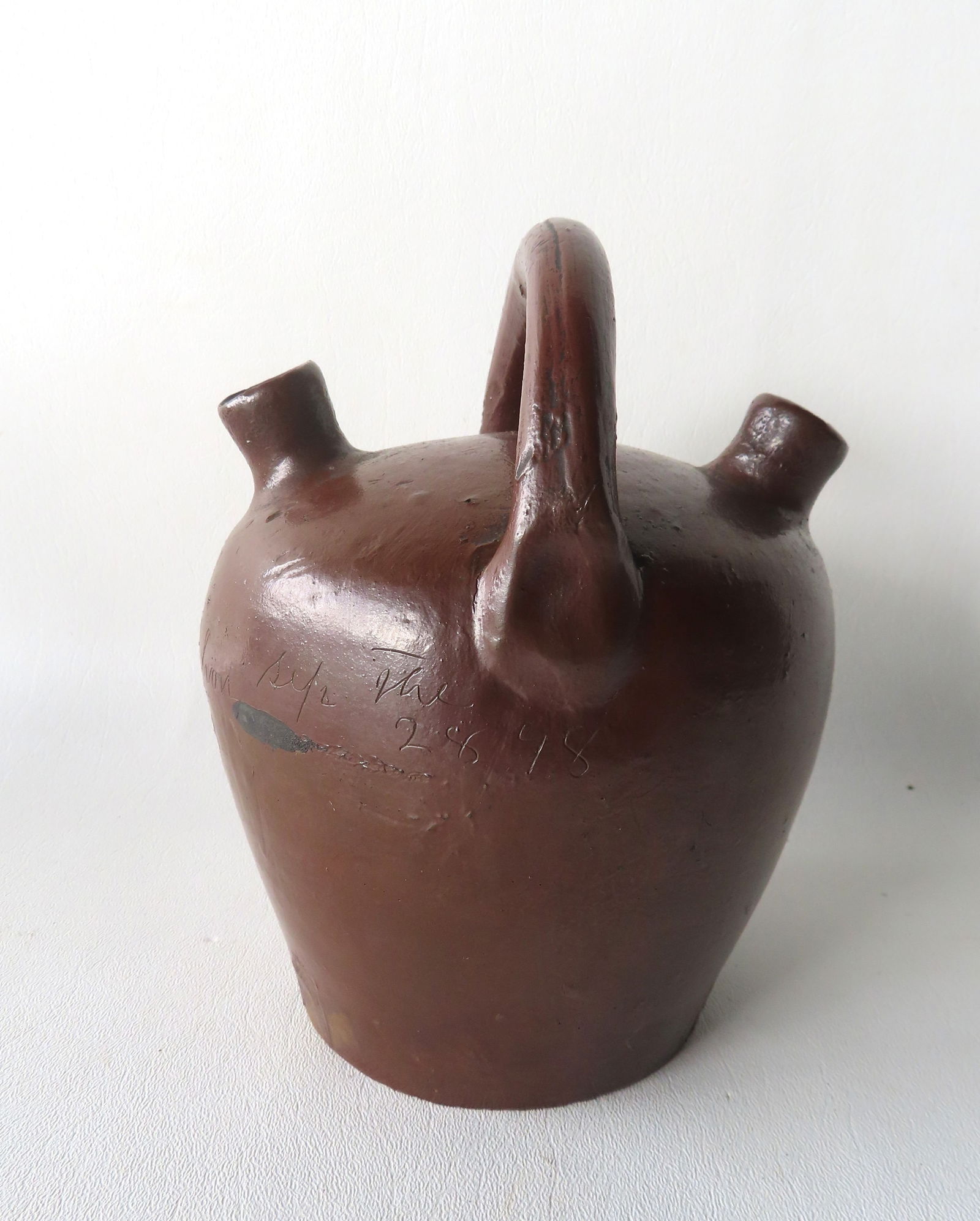 A stoneware or redware double spout jug in Albany slip, possibly a ceremonial or wedding jug,: A stoneware or redware double spout jug in Albany slip, possibly a ceremonial or wedding jug, allowing 2 persons to share the contents. The jug with single loop handle, signed in script "I C Golerhon