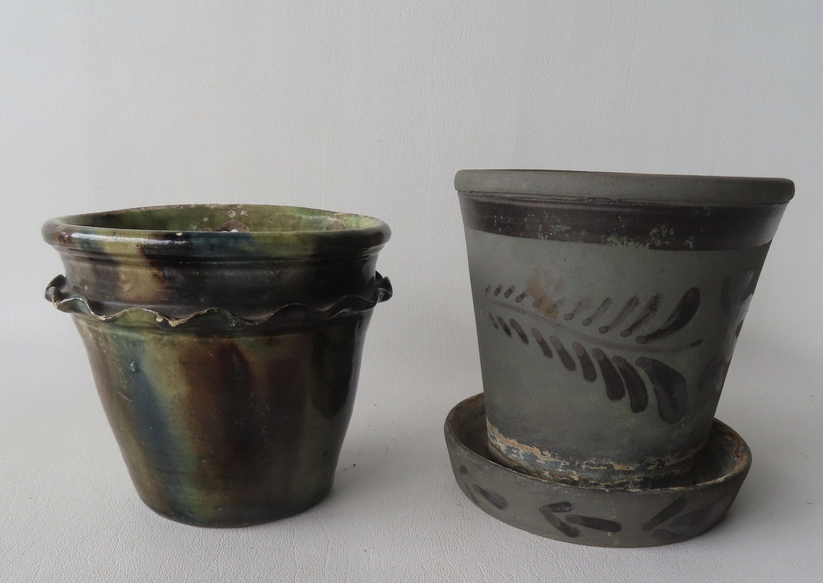 Two stoneware planters. The first decorated with a long cobalt blue leaf and with attached under: Two stoneware planters. The first decorated with a long cobalt blue leaf and with attached under plate - good condition - measures 5 1/4" diameter x 5 1/2"H; and the second, for wall mounting, ruffled