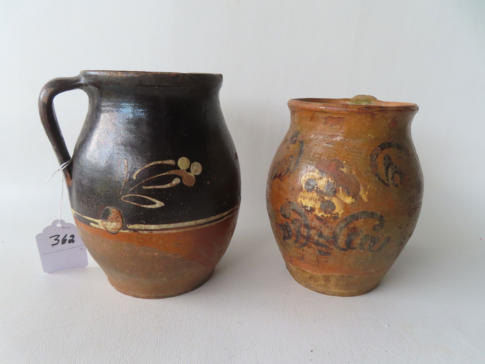 Two redware pitchers with unusual slip decorations but with extensive losses to glazing. The largest: Two redware pitchers with unusual slip decorations but with extensive losses to glazing. The largest measures 8 1/2"H x 7"W.