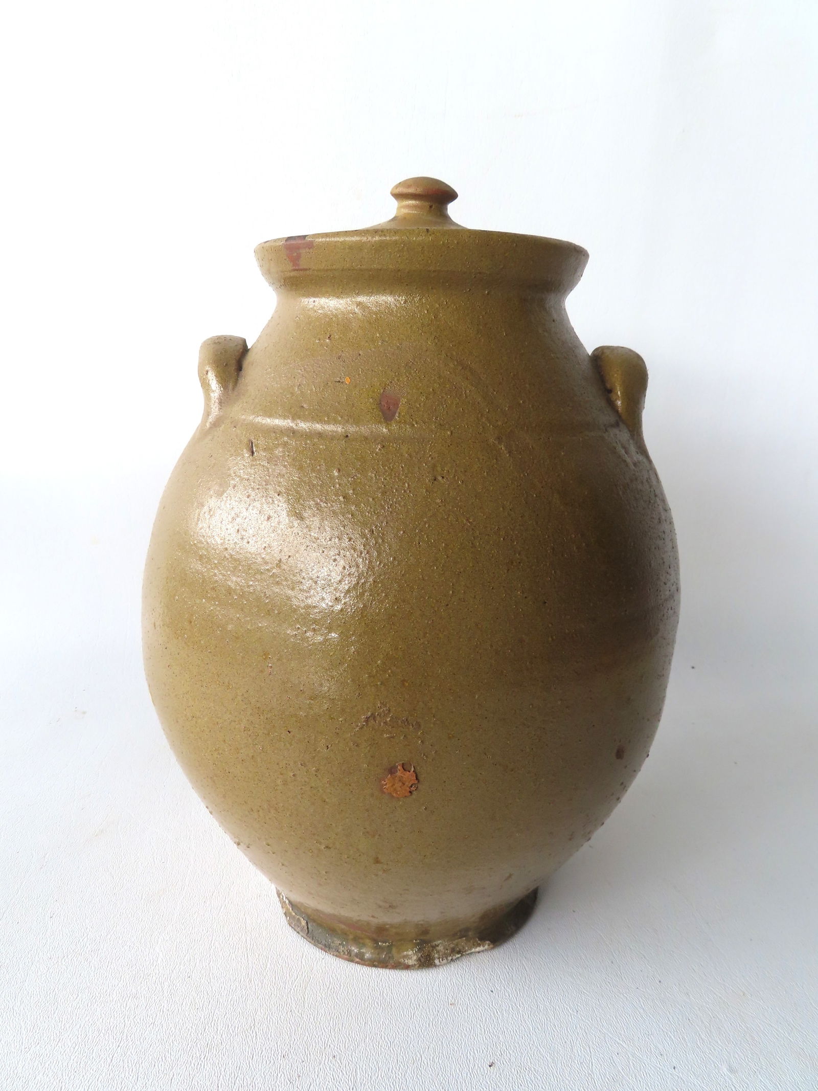 An unusual redware ovoid jar in mustard glaze which appears to be original, with double handles,: An unusual redware ovoid jar in mustard glaze which appears to be original, with double handles, original lid, and footed base, early 19th century. Measures with lid 11 1/4"H x 7 1/2"W. Small chips to