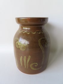 A stoneware jar with Albany glaze and decorated wish a lighter brown slip in the form of stylized