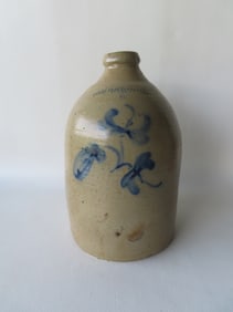 A stoneware jug decorated with a cobalt blue flower with the impressed mark of "WELLS CRAFTS & WELLS