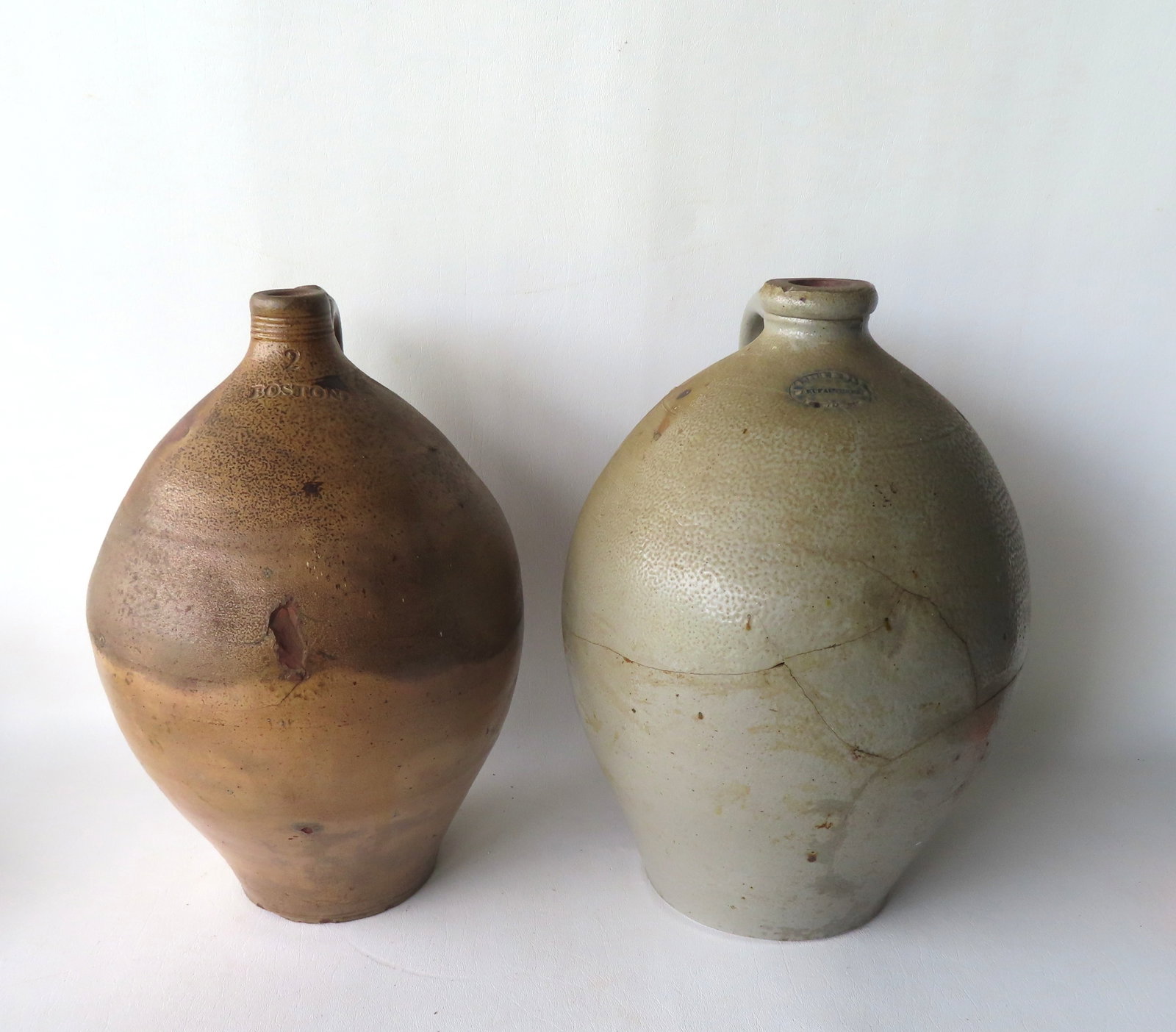 Two early ovoid jugs, both 2 gallon size. The first with concentric rings around neck, and having a: Two early ovoid jugs, both 2 gallon size. The first with concentric rings around neck, and having a tooled handle with the impressed mark of "BOSTON" - some staining, otherwise good condition - measur