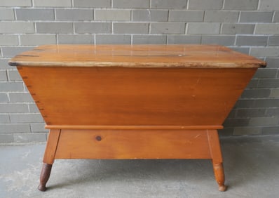 A pine dovetailed dough box with removable top - the base with canted sides, turned legs leading to