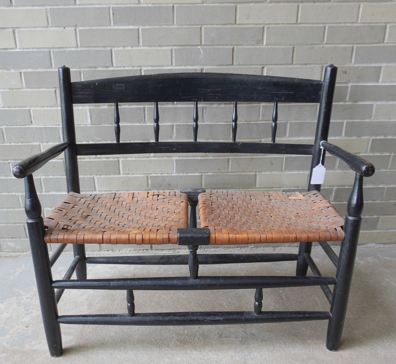 A half-spindle buggy bench with woven cane seat, turned arms, legs and cross stretchers, early to: A half-spindle buggy bench with woven cane seat, turned arms, legs and cross stretchers, early to mid 19th century. Old black paint, but not original, and in good condition. Measures 34 1/2"W x 16 1/2