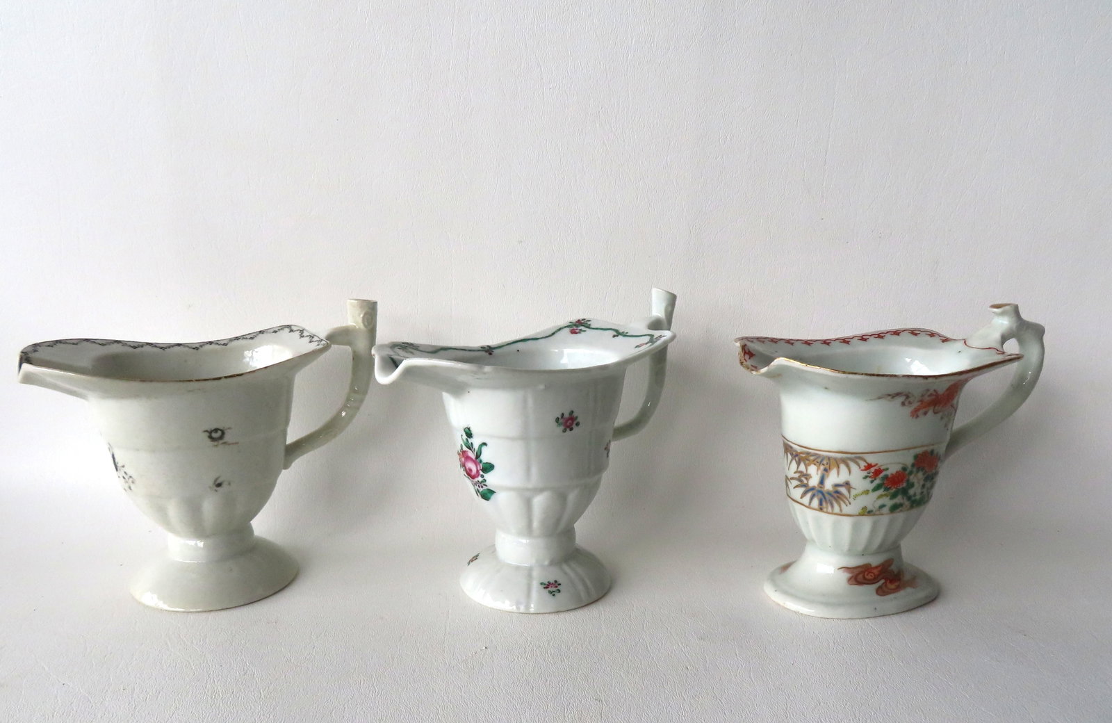 Three Chinese porcelain helmet pitchers, all decorated with floral sprigs, 18th century. Two in very: Three Chinese porcelain helmet pitchers, all decorated with floral sprigs, 18th century. Two in very good condition with no damage or repairs, and the other with chips and hairline at spout, small chi
