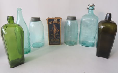 Grouping of 7 vintage glass bottles and jars including: Two gin bottles, one in light green marked