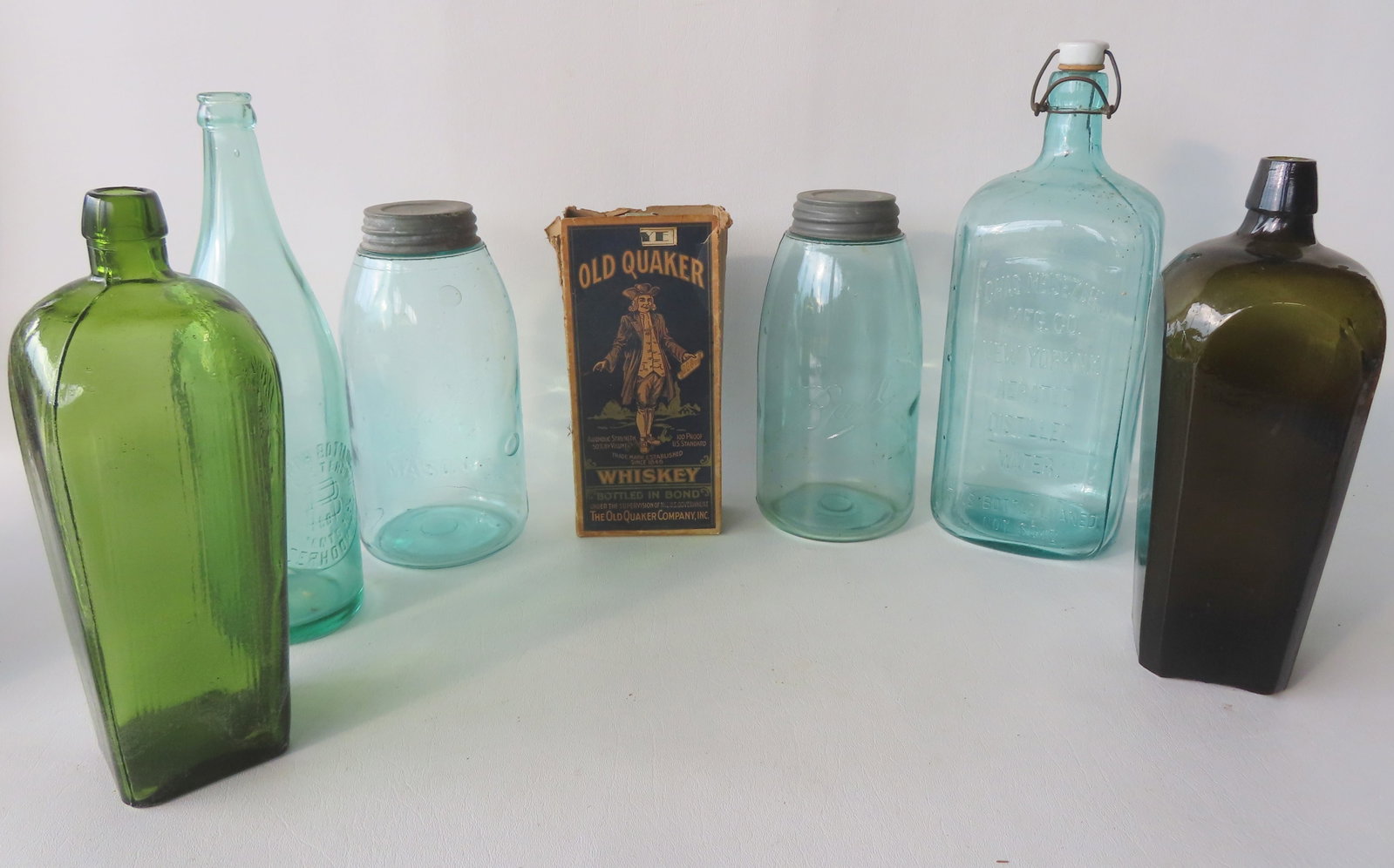 Grouping of 7 vintage glass bottles and jars including: Two gin bottles, one in light green marked: Grouping of 7 vintage glass bottles and jars including: Two gin bottles, one in light green marked with "M" on the bottom and the other in dark green - both in very good condition, no damage - the lar