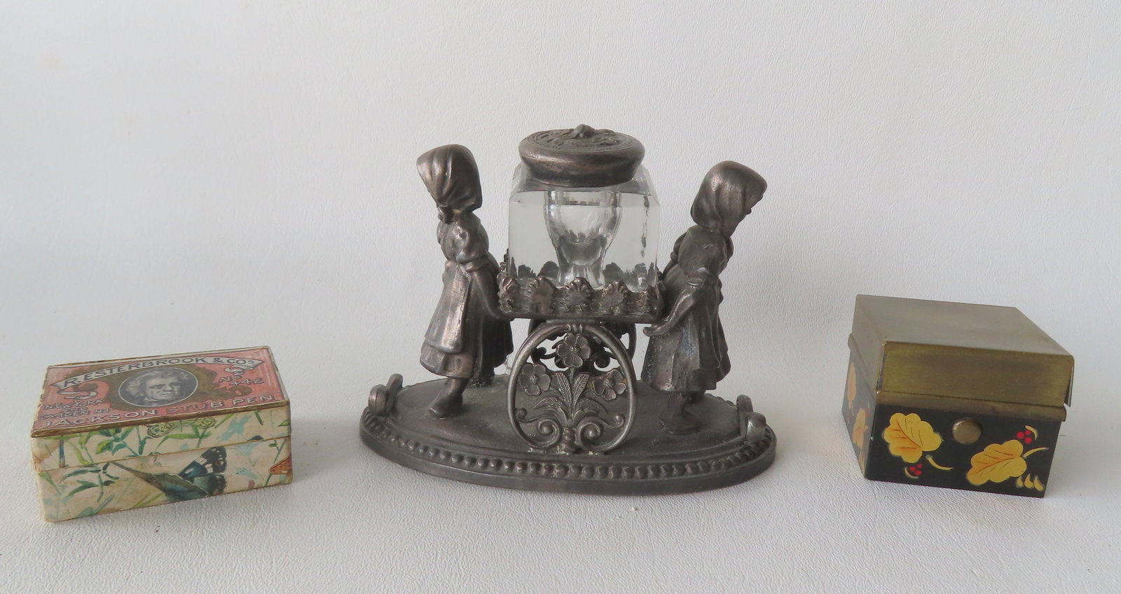 Three vintage desk articles including: A figural silver plated inkwell of 2 young girls holding cart: Three vintage desk articles including: A figural silver plated inkwell of 2 young girls holding cart containing inkwell signed on base "Waters & Thorp / Extra / New York" - this company active in New 