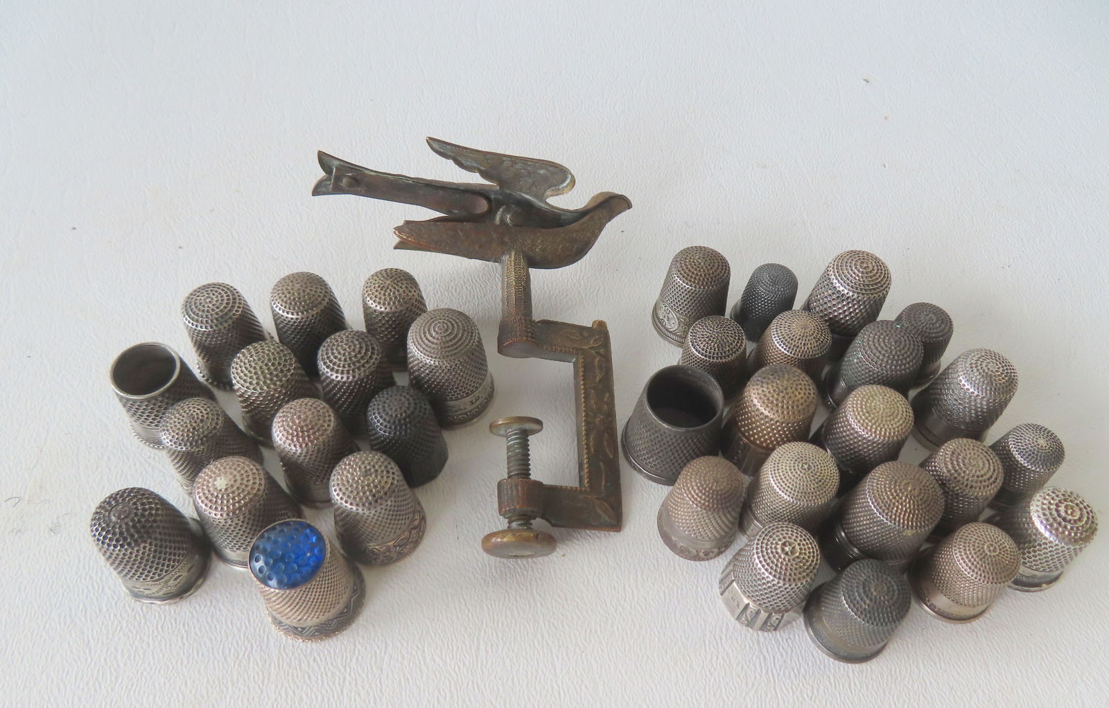 Grouping of 34 vintage silver thimbles and a Victorian brass sewing bird. All appear to be late 19th: Grouping of 34 vintage silver thimbles and a Victorian brass sewing bird. All appear to be late 19th to mid 20th century including 20 thimbles marked "Sterling". Most in used but good condition. Sever