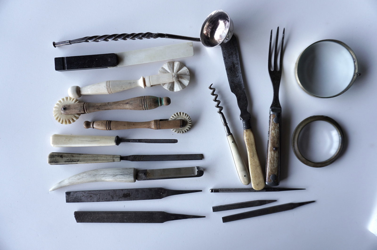 A grouping of domestic tools and implements including 7 with bone handles, 1 with stag horn handle,: A grouping of domestic tools and implements including 7 with bone handles, 1 with stag horn handle, 2 wooden pie crimpers, a silver toddy ladle (appears to have a repair to handle), 2 lenses, and 5 sm