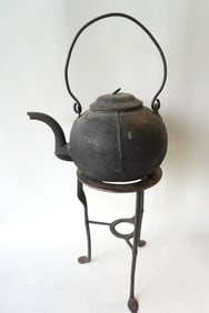 Two early iron hearth items - a cast iron tea kettle and Q.A. iron trivet with spade feet.