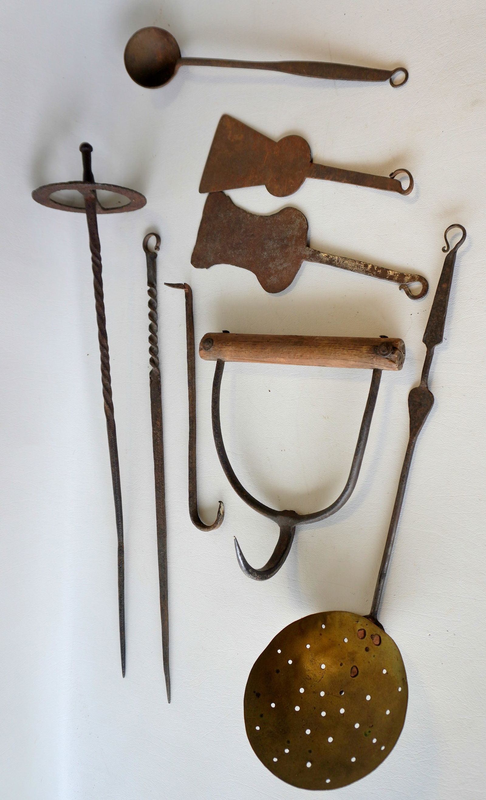A grouping of 8 pieces of early iron, most hand forged including: Spatulas, brass skimmer with iron: A grouping of 8 pieces of early iron, most hand forged including: Spatulas, brass skimmer with iron handle decorated with a heart, skewer, etc. The largest, the hand forged iron skewer measures 22 1/2