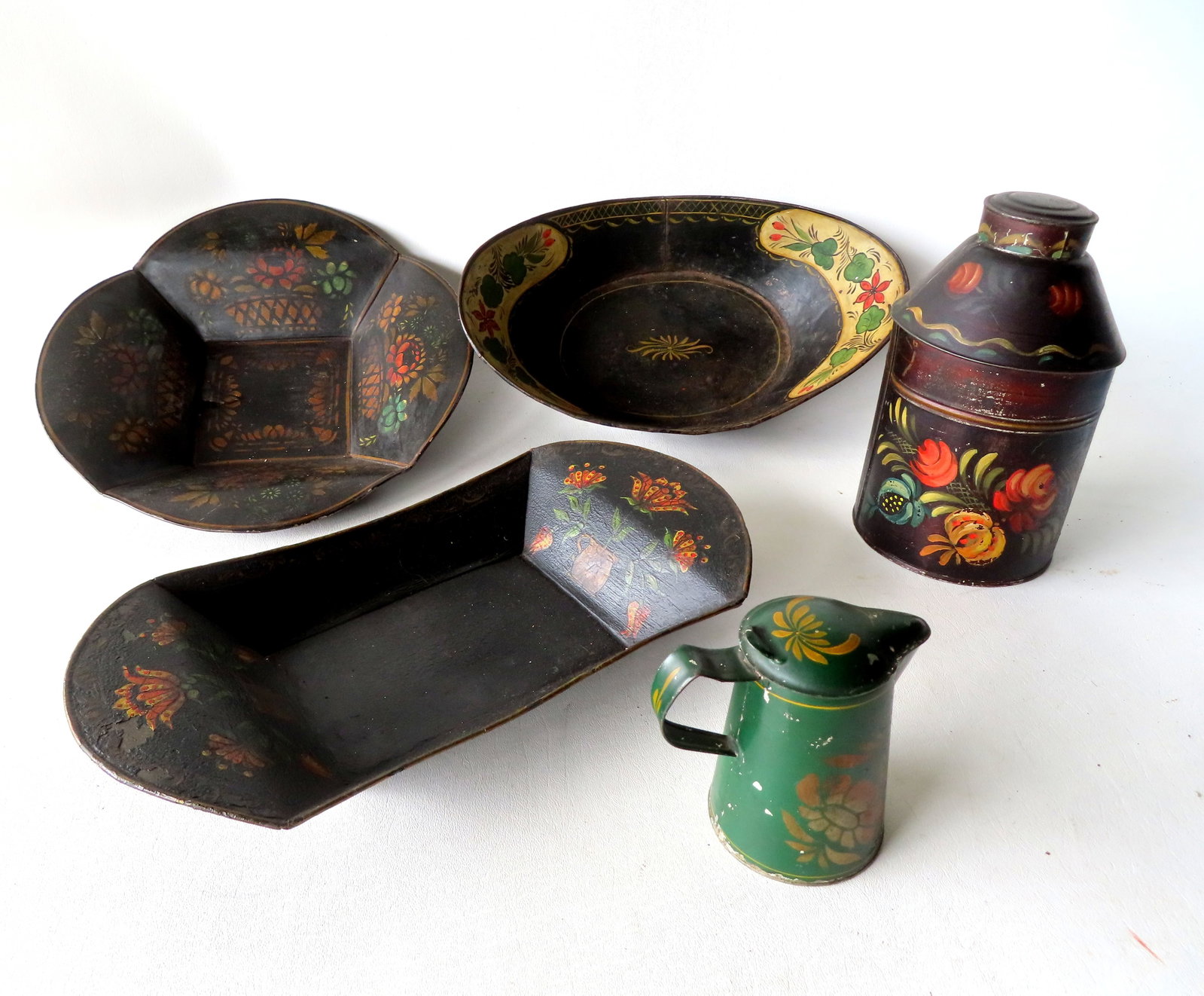 Five pieces of early toleware in original paint, mid 19th century and earlier. Includes a small: Five pieces of early toleware in original paint, mid 19th century and earlier. Includes a small covered pitcher stenciled "Molasses Cup" - very good condition - 4 1/2"H x 4 1/2"W; a hand painted tea c