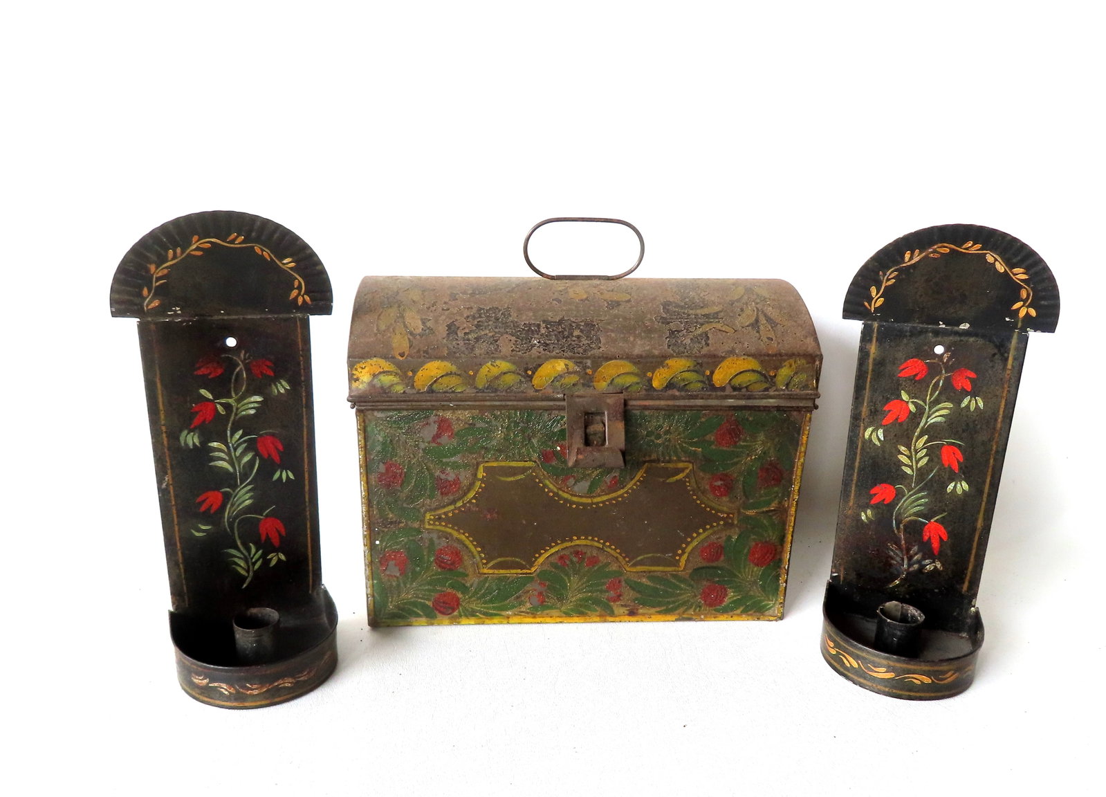 Three pieces of toleware including: A dome top box, in original worn paint, early to mid 19th: Three pieces of toleware including: A dome top box, in original worn paint, early to mid 19th century; and a pair of hand painted toleware candle wall sconces decorated with red flowers on vine, all o