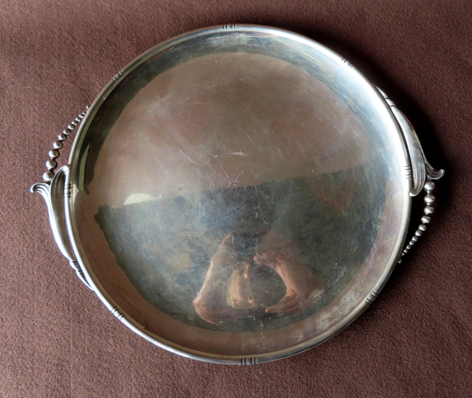 A Woodside sterling silver round tray with stylized floral handles in the Georg Jenson style, NY: A Woodside sterling silver round tray with stylized floral handles in the Georg Jenson style, NY circa 1900, some surface scratches but otherwise very good condition. Measures 16 1/4"W. Weighs 28.9 tr