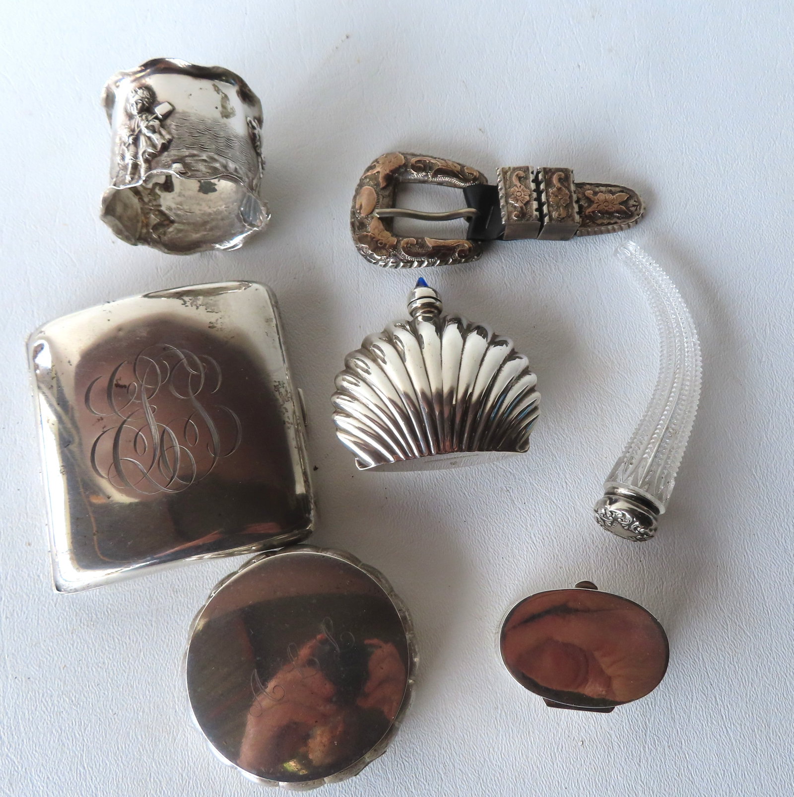 Grouping of sterling silver to include: Cigarette case, a designer Mexican scent bottle signed Hecho: Grouping of sterling silver to include: Cigarette case, a designer Mexican scent bottle signed Hecho En, a cut glass scent bottle with sterling cap, a lady's powder compact, a bill box, and a belt buc