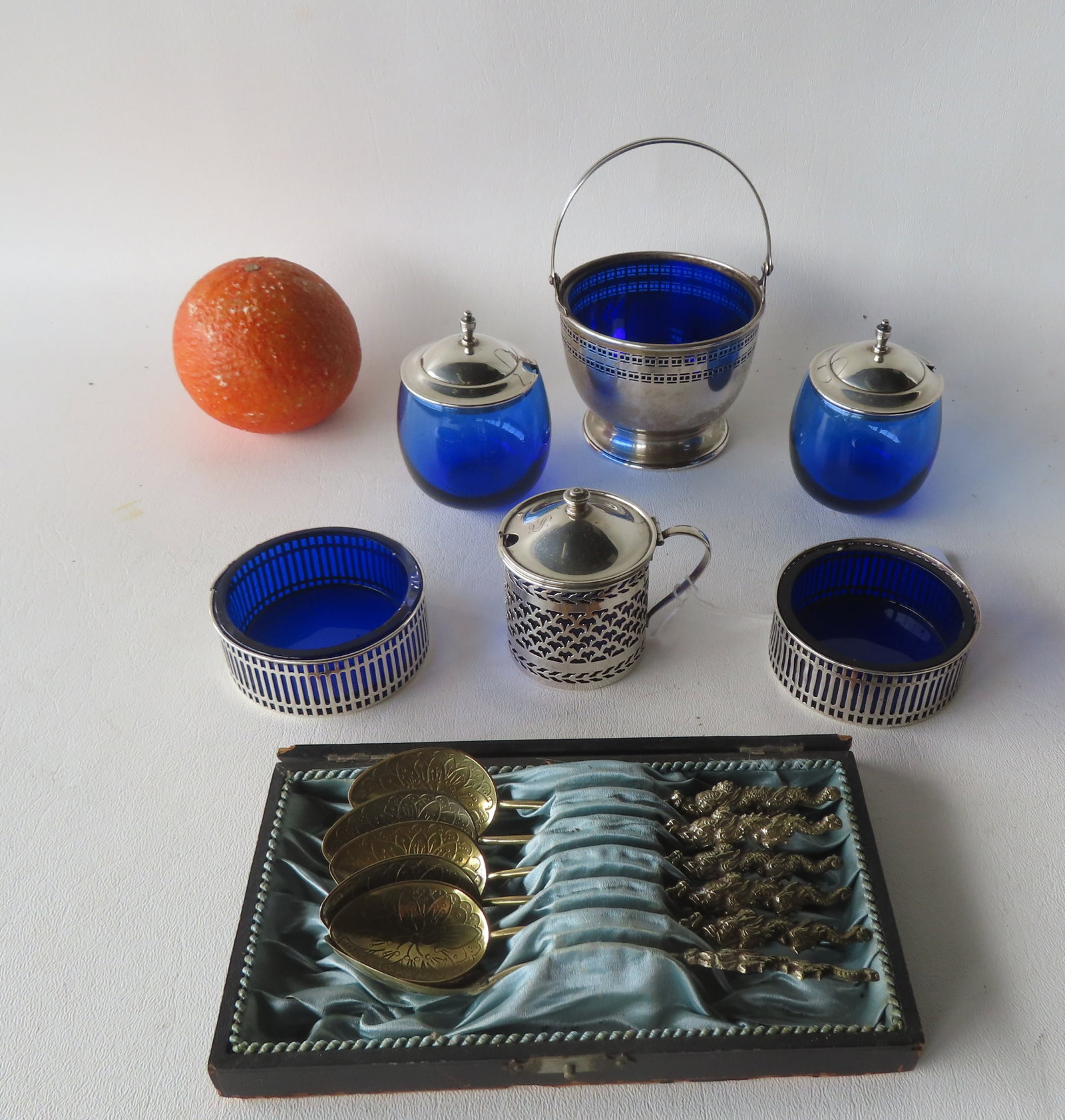 A sterling silver 6 piece condiment set with cobalt blue glass inserts, together with a boxed set of: A sterling silver 6 piece condiment set with cobalt blue glass inserts, together with a boxed set of fancy silver Nagasaki tea spoons with dragon shaped handles, all in very good condition. The larges