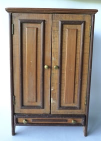 A primitive hand made doll's cupboard having 2 paneled doors over lower paneled drawer, constructed