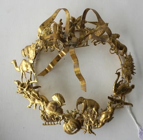 A brass holiday wreath decorated with many holiday figures for Christmas, Easter, Halloween,