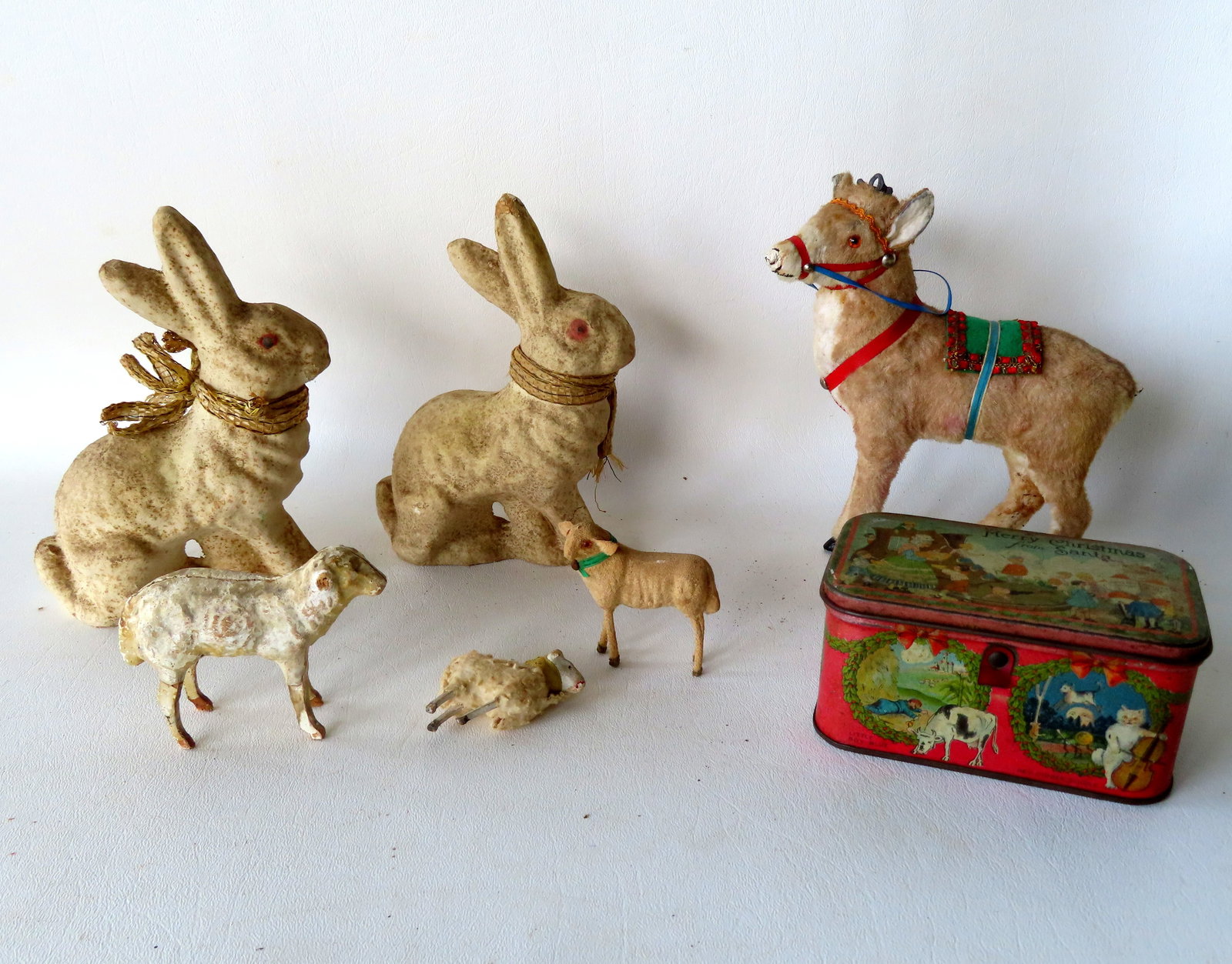 A grouping of mostly holiday toys including: A lithographed tin Christmas candy container - minor: A grouping of mostly holiday toys including: A lithographed tin Christmas candy container - minor use wear - early to mid 20th century; 2 paper mache Easter rabbit candy containers circa 1950; 3 minia