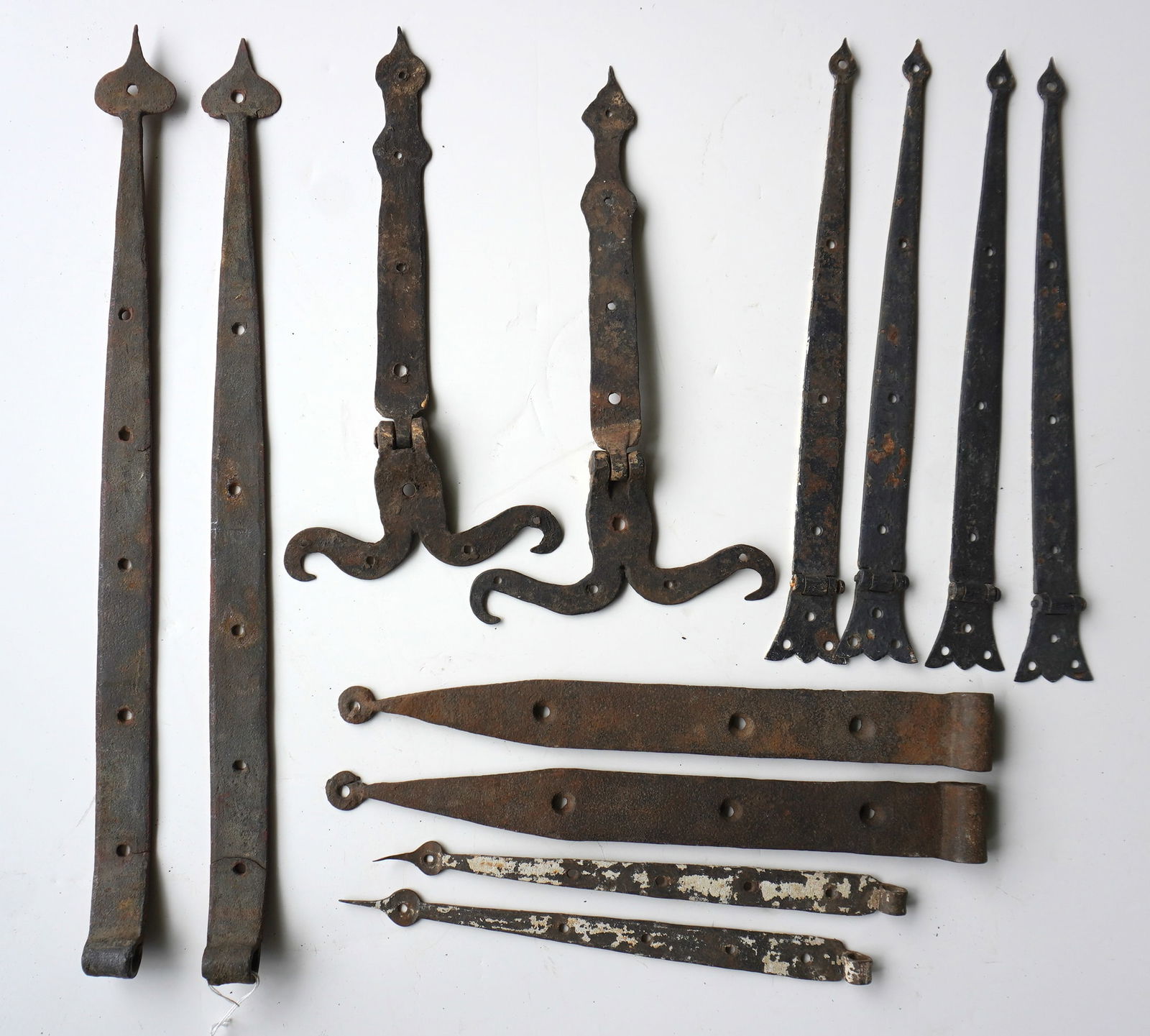 Six matched pairs of early hand forged iron strap hinges, late 18th to early 19th century.: Six matched pairs of early hand forged iron strap hinges, late 18th to early 19th century. Includes a pair of mustache hinges - 13 1/2"L x 6 3/4"W. All in good condition in old surfaces. The largest p