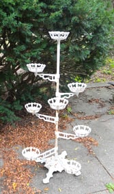 A cast iron plant holder with 8 movable arms in graduated sizes - 8"L to 13"L, each with receptacles