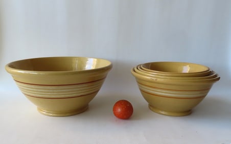 Grouping of 5 yellowware mixing bowls with rolled rims and footed bases. Includes a matching nested