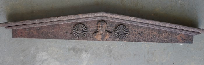 An architectural door pediment with 2 applied carved rosettes flanking a carved image of Admiral