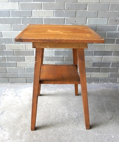A mustard colored grain painted work table with breadboard ends, tapered and splayed legs and lower