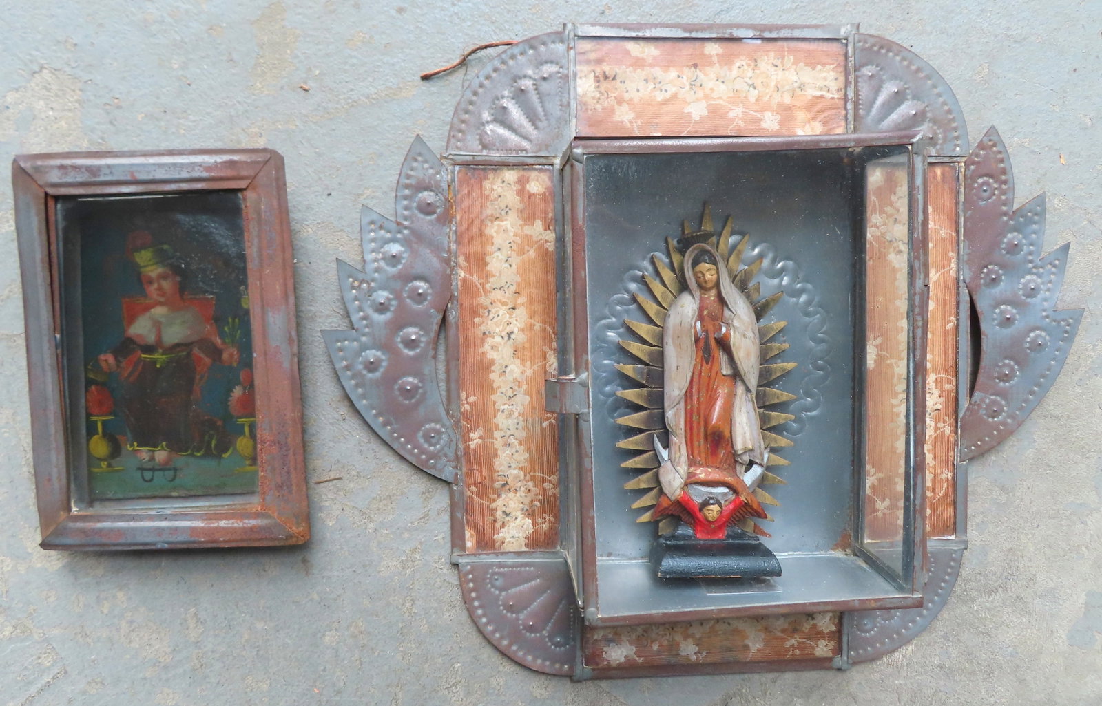 Two folk art Spanish Colonial Nichos in tin currently housing retablos. The first with a punched tin: Two folk art Spanish Colonial Nichos in tin currently housing retablos. The first with a punched tin outer border and having a hand painted inner border of flowers under glass - the nicho houses a han