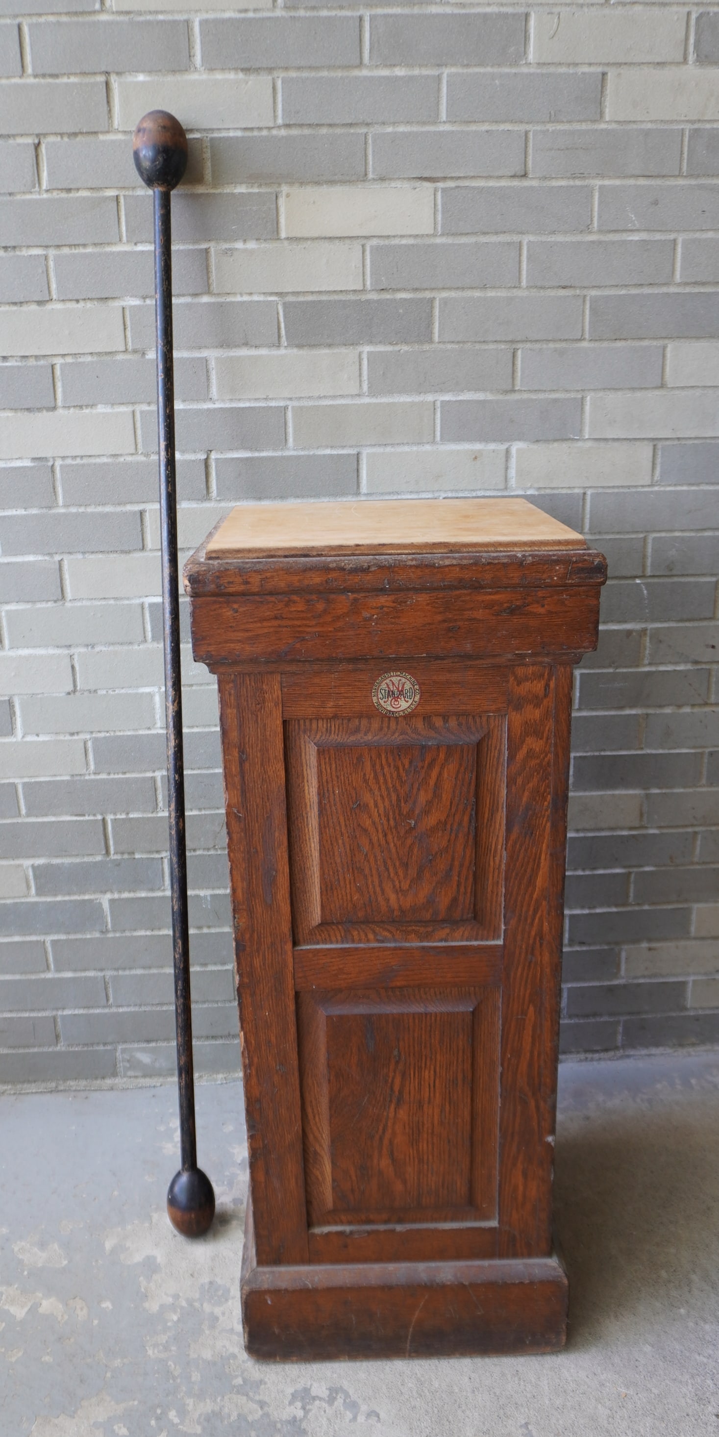 A signed Narragansett Machine Co. oak exercise wand box with raised panels, together with 1 wooden: A signed Narragansett Machine Co. oak exercise wand box with raised panels, together with 1 wooden wand. The wand, in original black paint with use wear, measures 58 1/2"L. The box was original used t