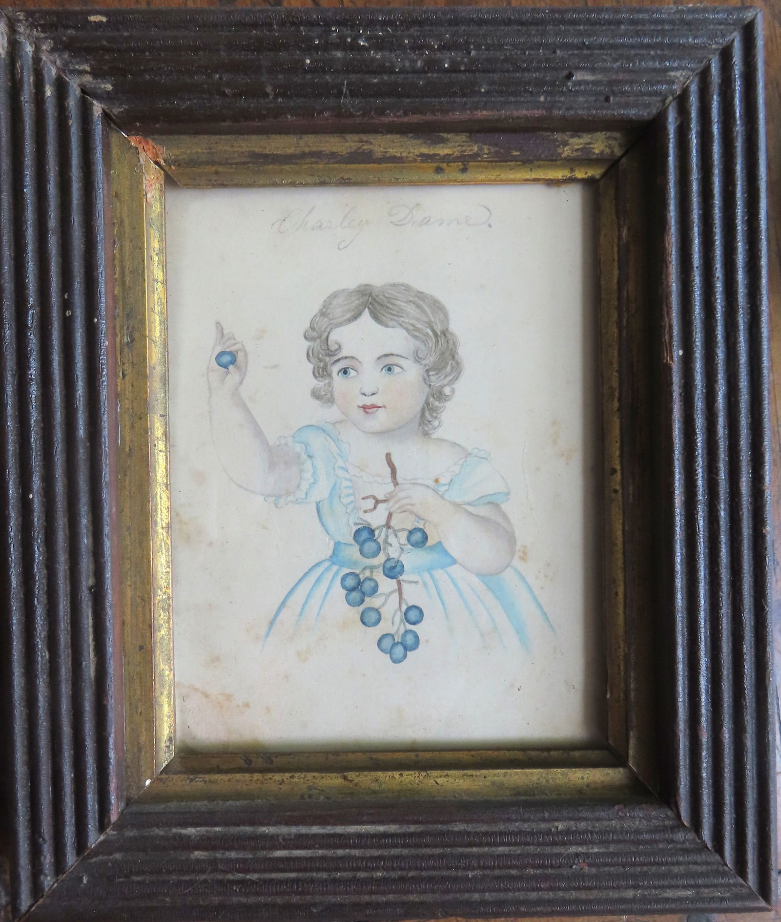 Miniature W/C portrait of small girl holding grapes, pencil signed above portrait "Charley Dame",: Miniature W/C portrait of small girl holding grapes, pencil signed above portrait "Charley Dame", mid 19th century and housed in a walnut frame from the same period. Total frame size 6 1/8" x 7 1/4".