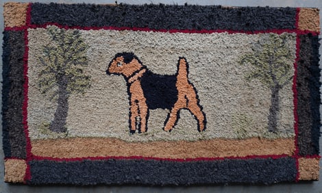 A folk art mounted hooked rug depicting a Spaniel dog standing between 2 trees - minor pulls in