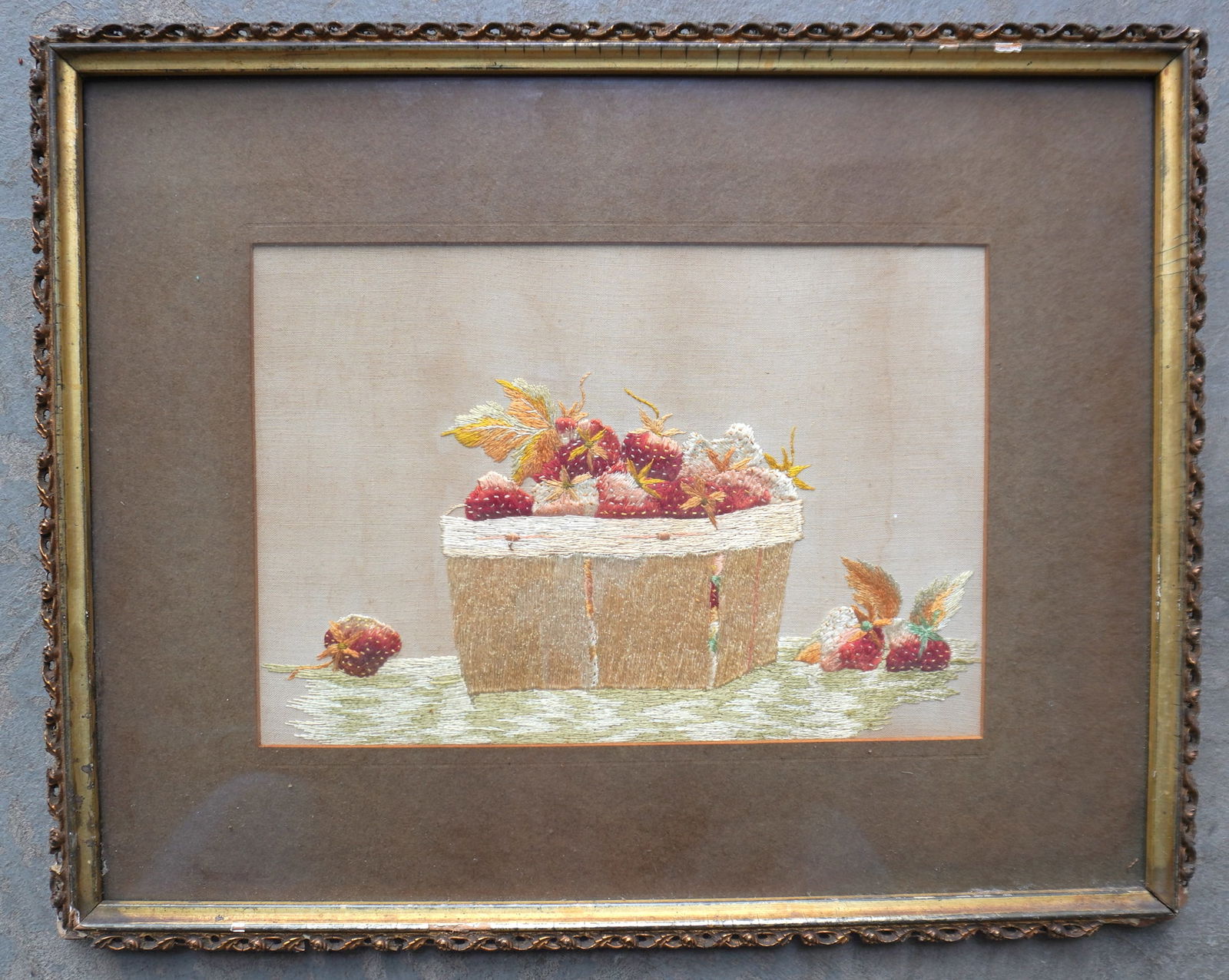 An early silk work embroidery depicting strawberries in a basket, mid 19th century or earlier. Size: An early silk work embroidery depicting strawberries in a basket, mid 19th century or earlier. Size within mat 7 1/4" x 10 3/4" - total frame size 13 3/4" x 17 1/4". The frame with minor losses in cor