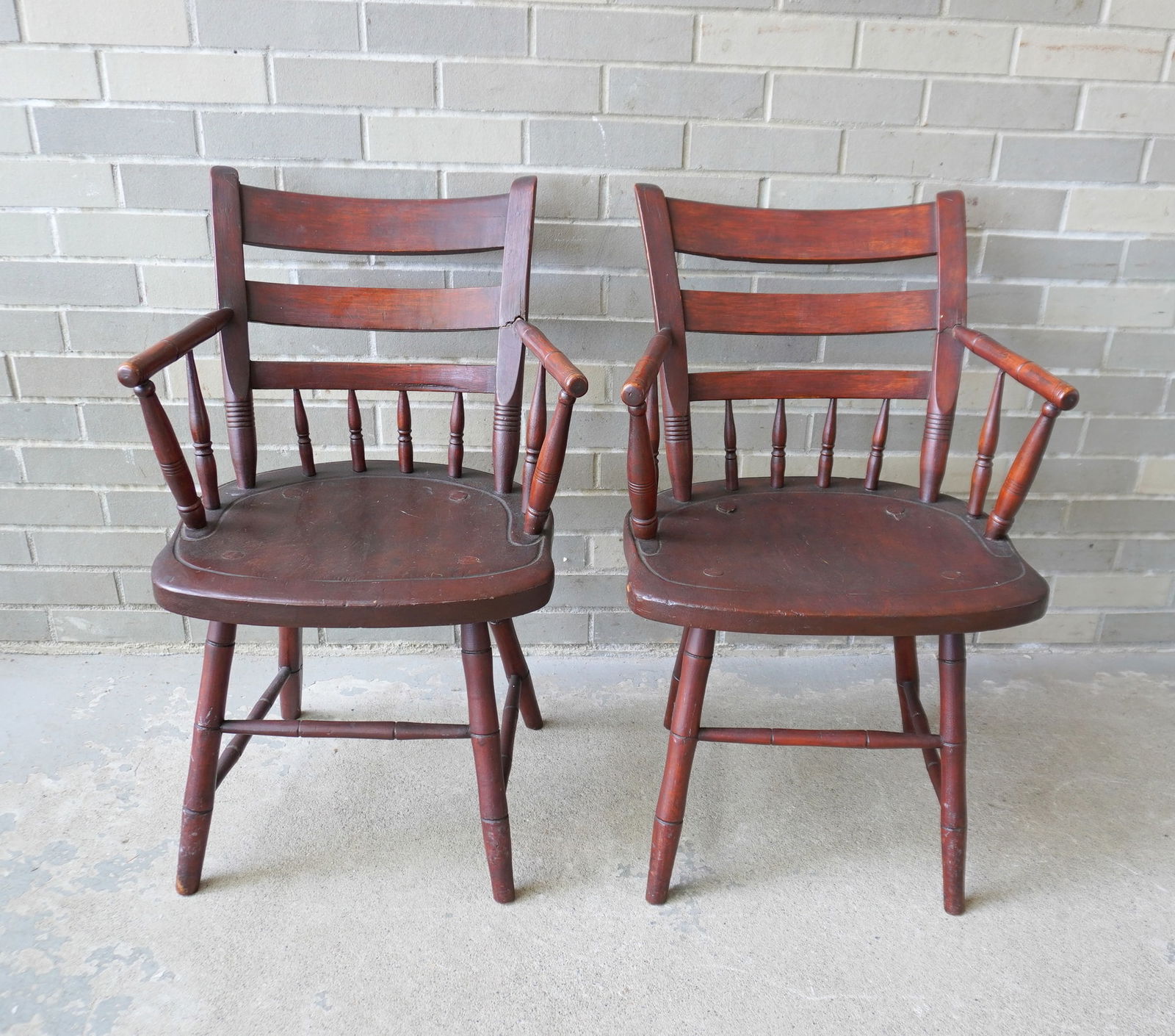 A pair of half spindle-back arm chairs with curved backs, rabbit ears, and Windsor type shaped: A pair of half spindle-back arm chairs with curved backs, rabbit ears, and Windsor type shaped saddle seats in old finish, circa 1815-25. Deaccessioned from the Crawford House Museum, Newburgh NY - no