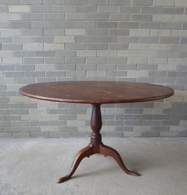 An American Queen Ann tilt-top tea table in original red paint. The turned pedestal leading to