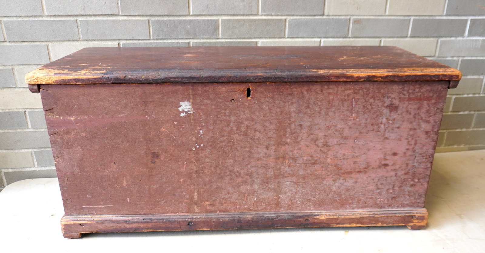 An early blanket box in original red stain with molded edge to lid, molded base, dovetailed: An early blanket box in original red stain with molded edge to lid, molded base, dovetailed construction, original cleats to lid attached with rosehead nails, original slatted feet, circa 1800. Wear t