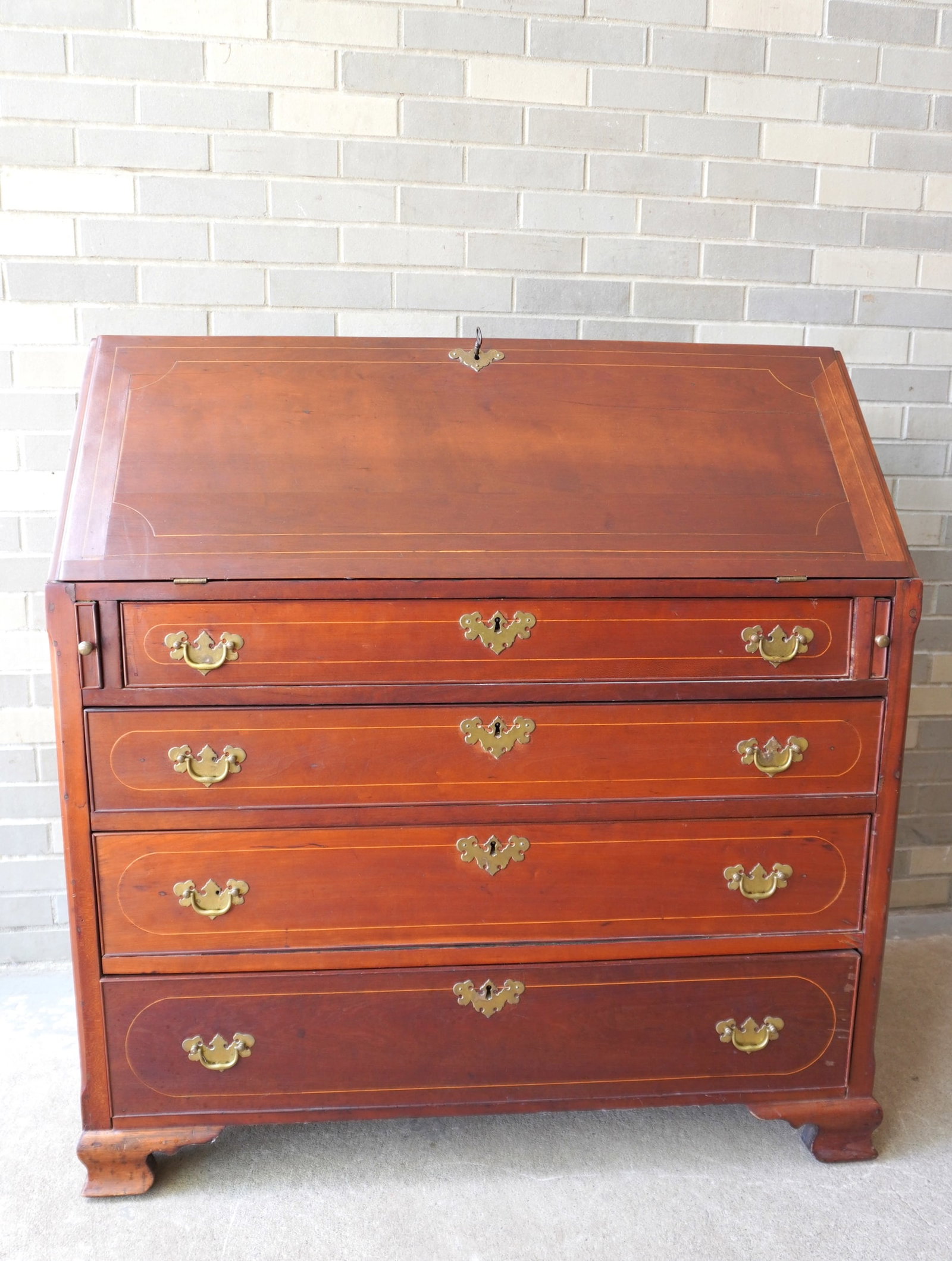 A transitional Chippendale cherry slant front desk with fitted interior with drawers and cubby units: A transitional Chippendale cherry slant front desk with fitted interior with drawers and cubby units - the case with 4 graduated drawers, is dovetailed at the top and rests on its original bracket bas
