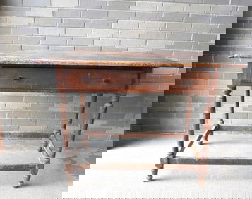 A 18th century tavern table with breadboard ends and center drawer, cross stretchers on turned legs.